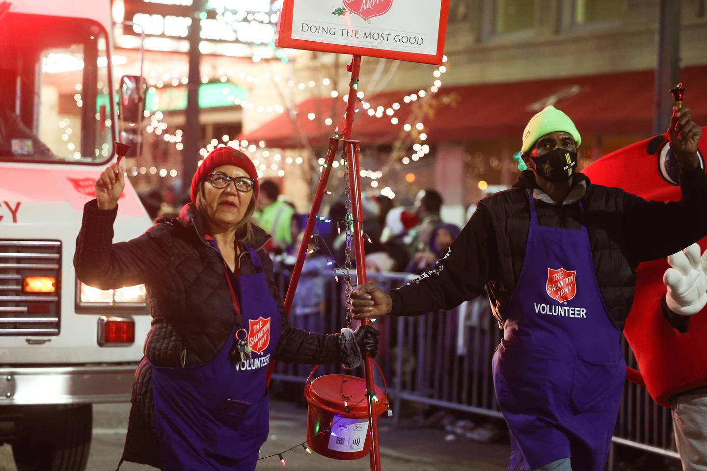 Salvation Army volunteers ring the bell as they walk along Chicago Street at the Light Up the Holidays Festival and Parade in downtown Joliet.