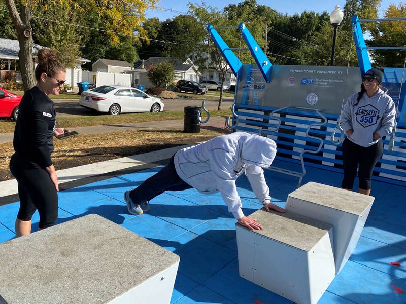 Brad Hughes demonstrates an assisted plank with encouragement from Sarah Nanouski and Tara Francisco.
