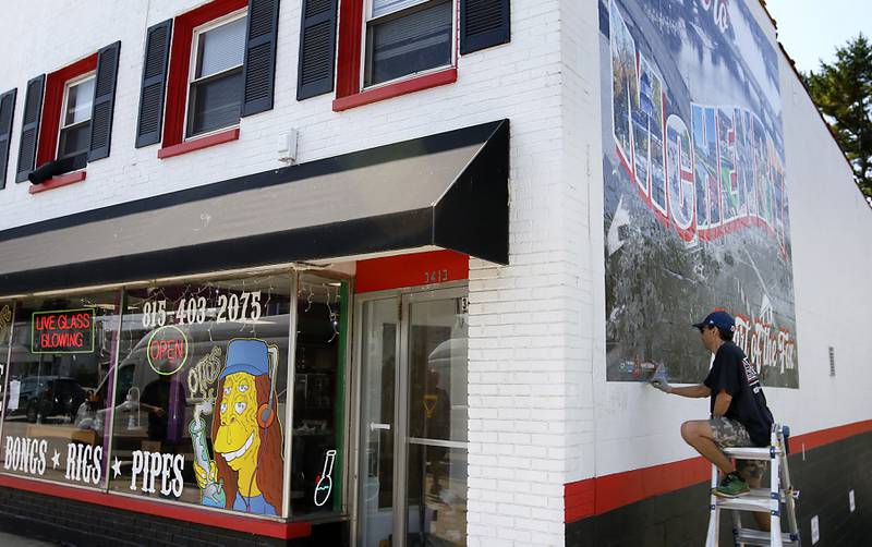 Chris Szymczuch, of Vindictive Vinyl, works on installing a vital mural on Thursday, June 19, 2025, on the side of a building at 3413 W. Elm St, in McHenry.