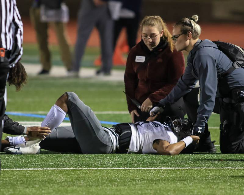 Oswego East's Robert Tyre Jones III (9) is tended to after suffering an ankle injury during Class 8A Playoff football game between Oswego East at York.  Oct 28, 2022.