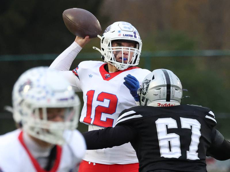 Lakes’ Ean Ankney delivers a pass just ahead of the pressure of Kaneland's Garrett Herst Saturday, Nov. 1, 2025, during their first round playoff game at Kaneland High School in Maple Park.