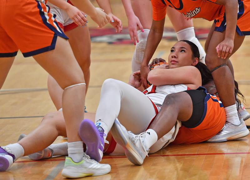 Benet’s Emma Briggs appears to rest comfortably while offered many hands up after she tied up with a Whitney Young player underneath her during a Coach Kipp Hoopsfest game on January 19, 2026 at Benet Academy in Lisle.