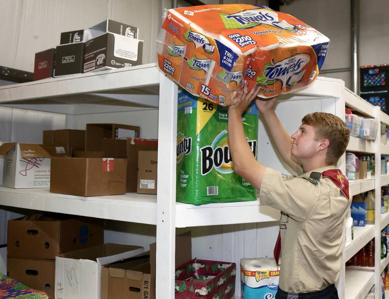 Billy Eby stocks paper towels on shelves he built as his Eagle Scout Project at Between Friends Food Pantry of Sugar Grove on Wednesday, June 8, 2022.