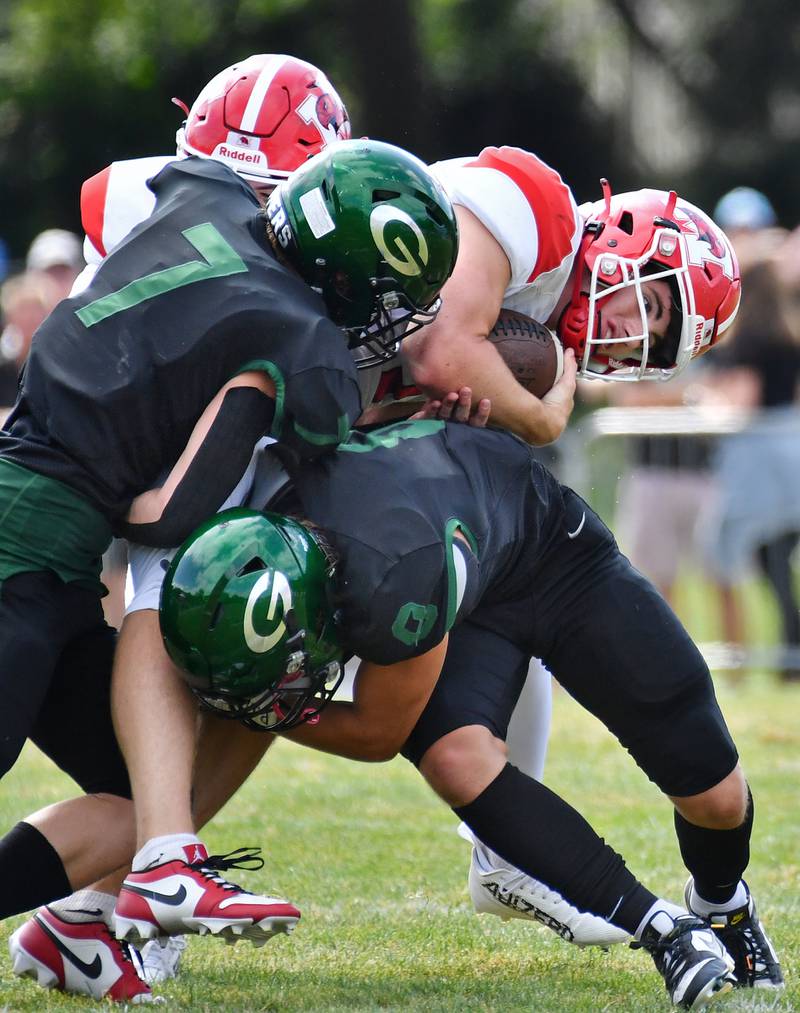Marist quarterback Owen Winters is stopped by Glenbard West tacklers Will Meyer (7) and Eli Limouris during a game on Aug. 26, 2023 at Glenbard West High School in Glen Ellyn.