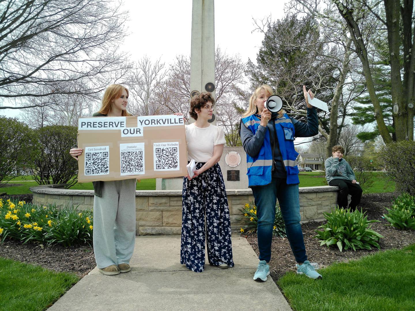 Resident Leesa Poss (right) addresses a group of protesters at the "Say No To Data Centers" event in Yorkville on April 11, 2026. Poss is joined by residents Sophia Yurt (left) and Alicia Castillo.