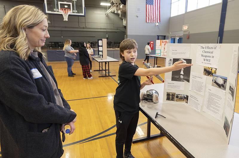 Challand Middle School sixth grader Liam Schilling presents his research of the effects of chemical weapons to his mom Krista Buckley Thursday, March 6, 2025, during a STEM Fair at the school.