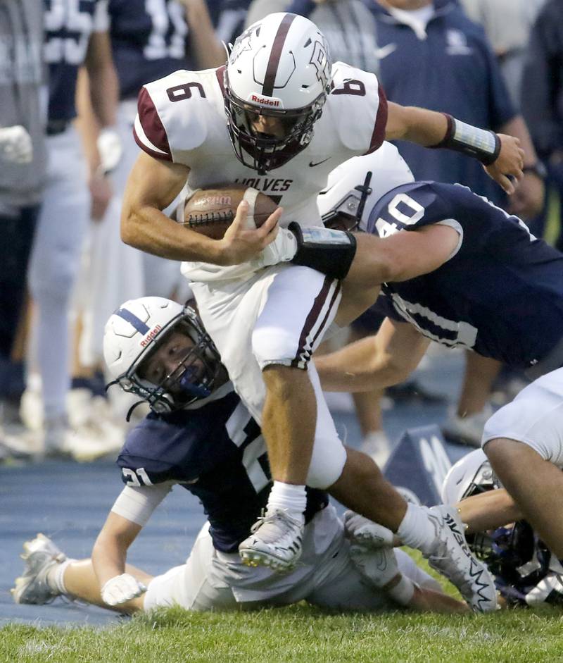 Prairie Ridge's Luke Vanderwiel fights for extra yard against Cary-Grove's Tanner Hurley (left) and Cary-Grove's Logan Abrams (right) during a Fox Valley Conference football game on Friday, Aug. 29, 2025, at Cary-Grove High School in Cary.