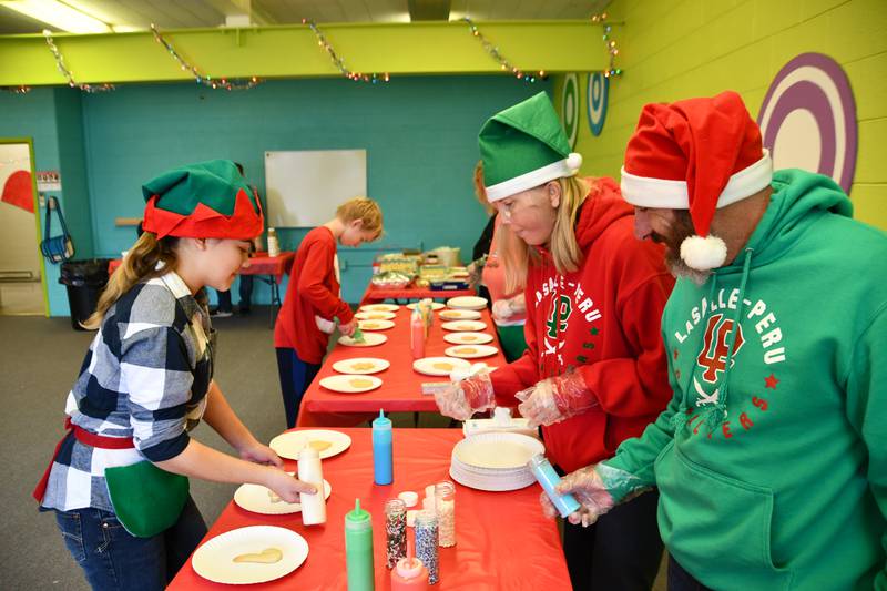 Eden Galvan decorates a cookie Saturday, Dec. 4, 2021, with the assistance of Mike and Linda Battagla at the Grove Center in La Salle.