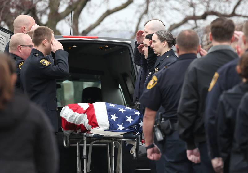 DeKalb County Sheriff’s Deputies salute as the flag-draped gurney carrying the body of DeKalb County Sheriff’s Deputy Christina Musil is removed from the Hearse Monday, April 1, 2024, at Butala Funeral Home following the processional honoring the fallen officer. Musil, 35, was killed Thursday while on duty after a truck rear-ended her police vehicle in Waterman.