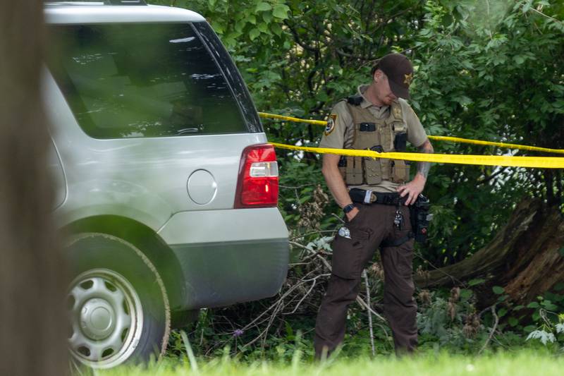 La Salle County Sheriff's Deputy stands behind caution tape at the crime scene of a double homicide on Thursday, July 17, 2025, on 42nd Road in Sheridan.