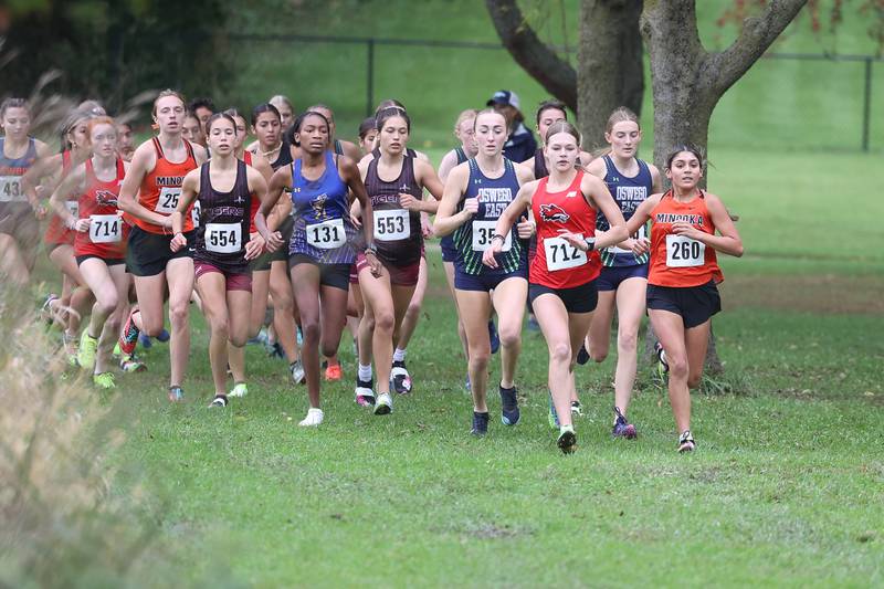 Yorkville’s Sophia Keeler (712) and Minooka’s Maya Ledesma lead the pack around the first turn in the Southwest Prairie Conference meet at Channahon Park in Channahon on Friday, Oct. 13, 2023.