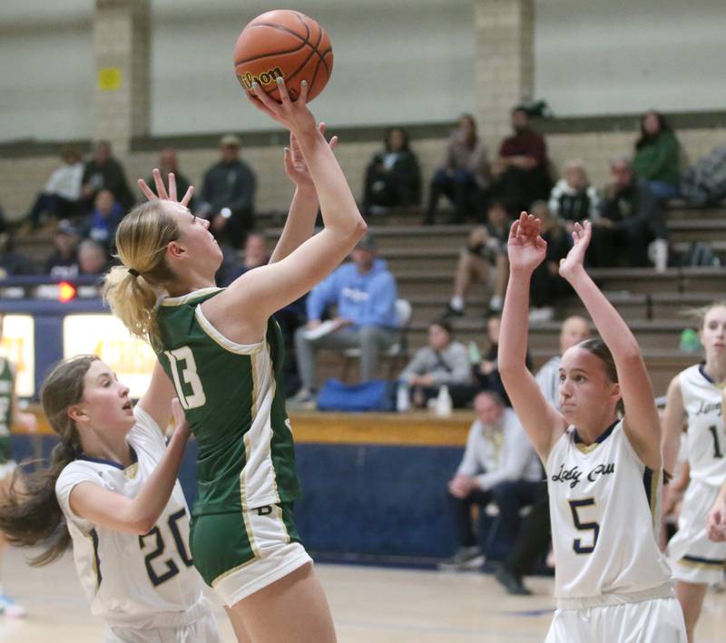 St. Bede's Ashlyn Ehm runs in the lane to take a shot over Marquette's Kaitlyn Davis and Chloe Larson on Monday, Nov. 27, 2023 in Bader Gym at Marquette High School.