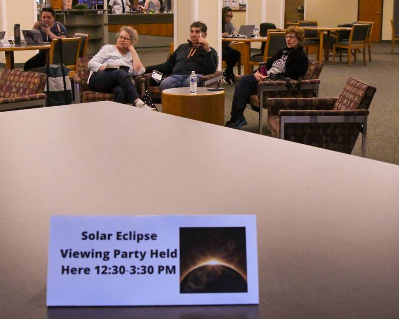 Lori Davis, right, of Wheaton, Tony Cardellino, Wood Dale, and Rita Agurre Bloomingdale all watch the tv feed streaming from Kerriville, Texas at the Wheaton library as the solar eclipse was taking place before heading out to view the solar eclipse themselves on Monday April 8, 2024.