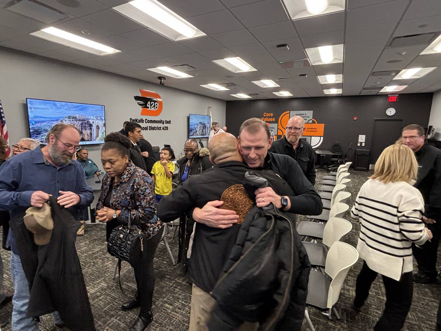 Billy Hueramo embraces Clinton-Rosette Middle School principal Brant Boyer at a Jan. 5, 2026, meeting of the DeKalb School District 428 Board of Education.