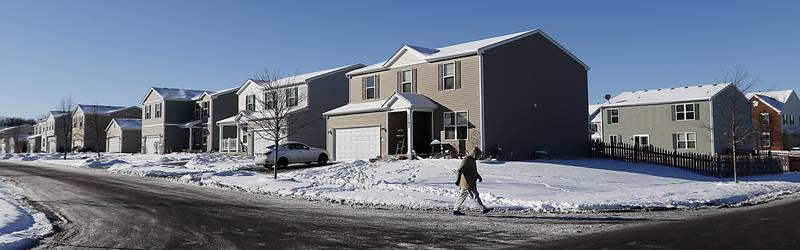 A man walks past a house the morning of Tuesday, Jan. 25, 2022, in the 1700 block of Yasgur Drive, where a shooting occurred Monday evening.