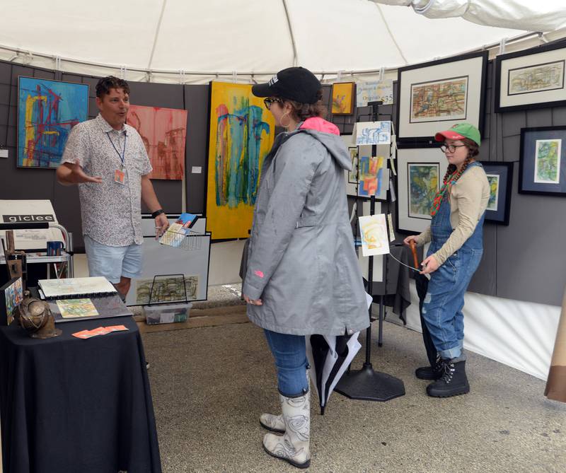Aaron Douglas Parks of Mount Prospect discusses his art work with (left) Kirsten Charlton and her daughter  Aine during the LaGrange Art Fest held Sunday Sept 11, 2022.
