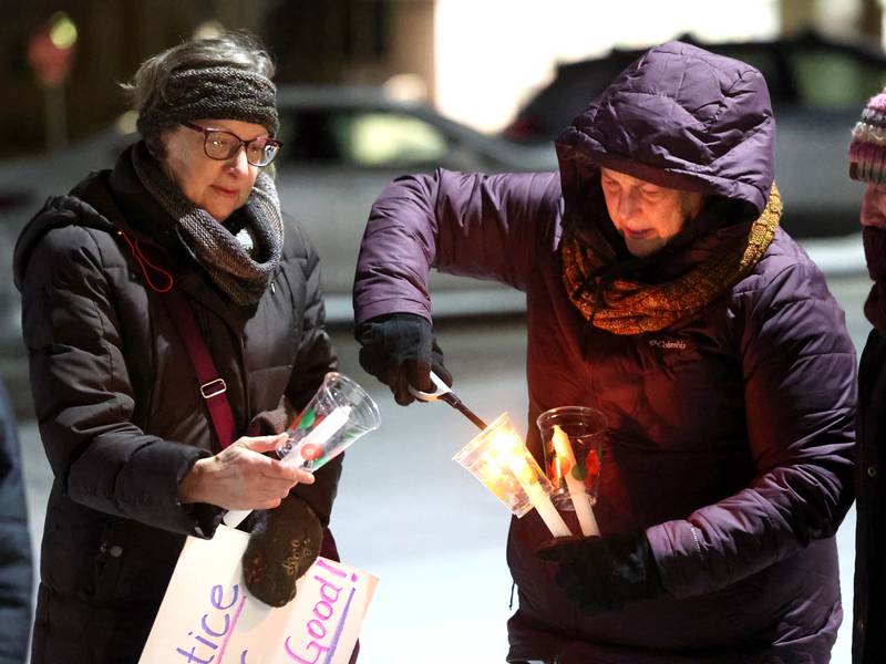 Jane School (left) and Chris Jones, both from DeKalb, light candles Monday, Jan. 26, 2026, during a vigil outside the DeKalb County Legislative Center in Sycamore after second shooting death in Minnesota involving ICE officers.
