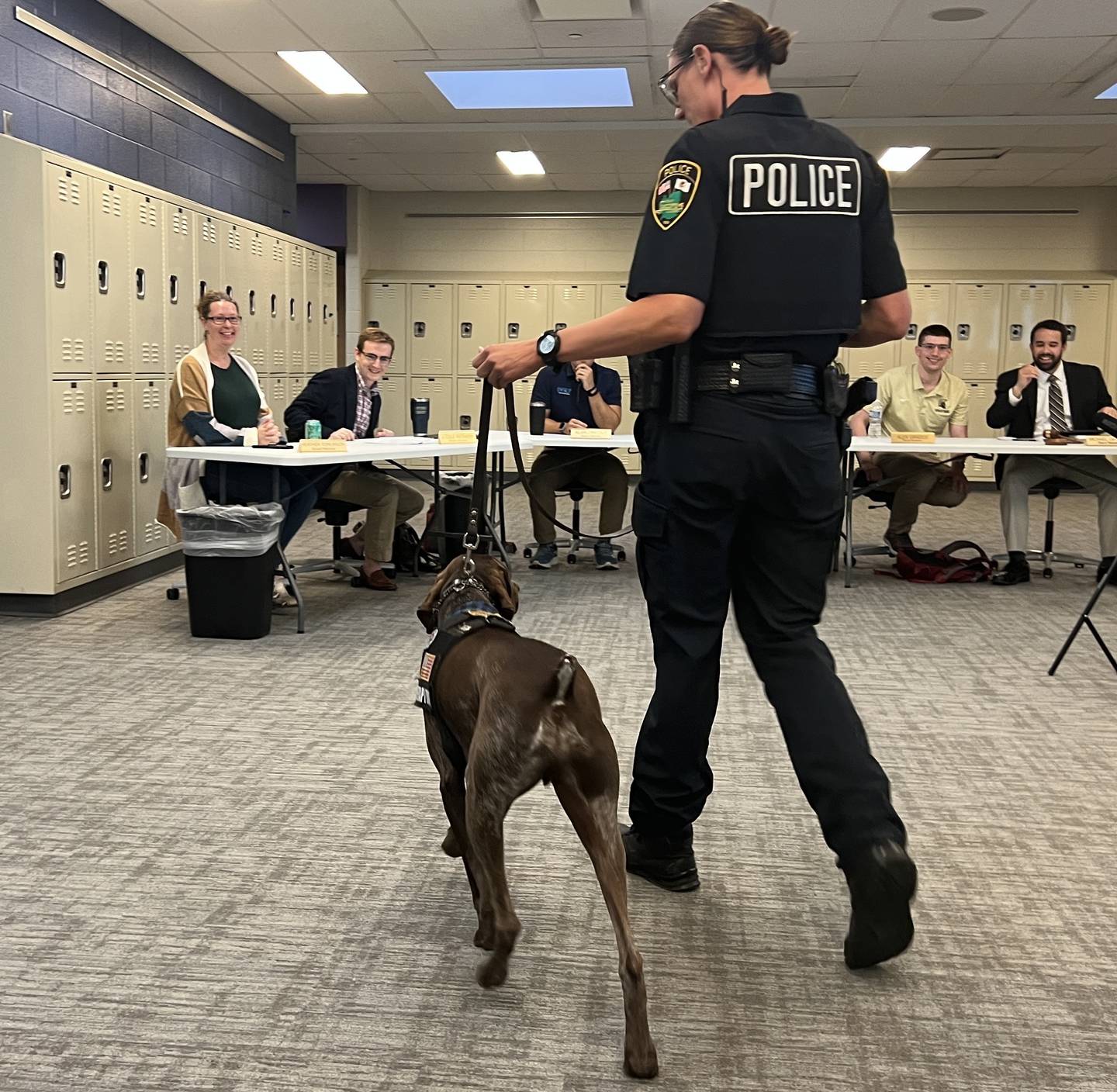 The Sycamore board of education, including first term members Heather Tomlinson and Cole Regnery and veterans Alex Grados and Michael DeVito, get excited as school resource officer Kaitlyn Pederson walks her therapy dog, Dooley over for pets at Sycamore Middle School on June 24, 2025.