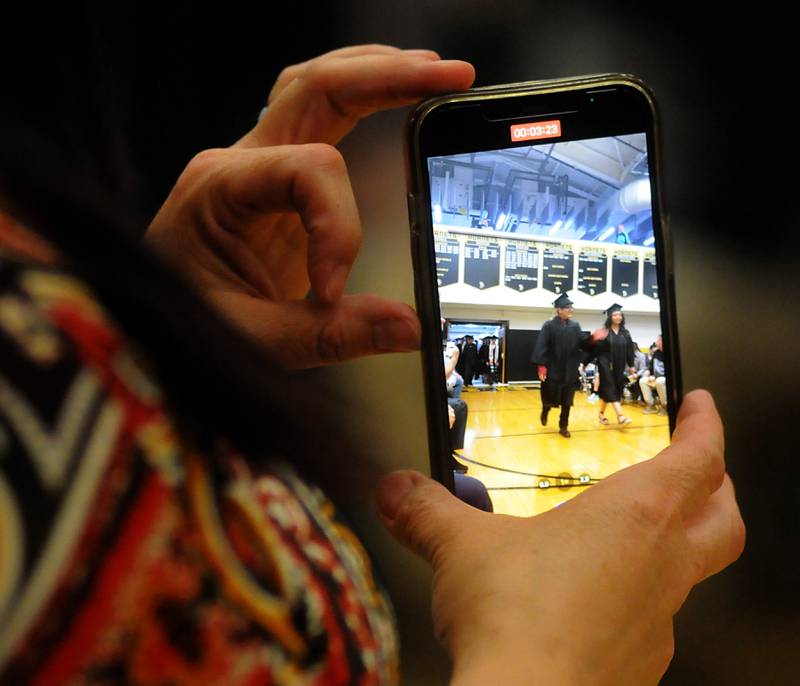 A parent records graduates as the walk into the gym Sunday, May 22, 2022, during the Harvard High School Commencement Ceremony in Harvard .