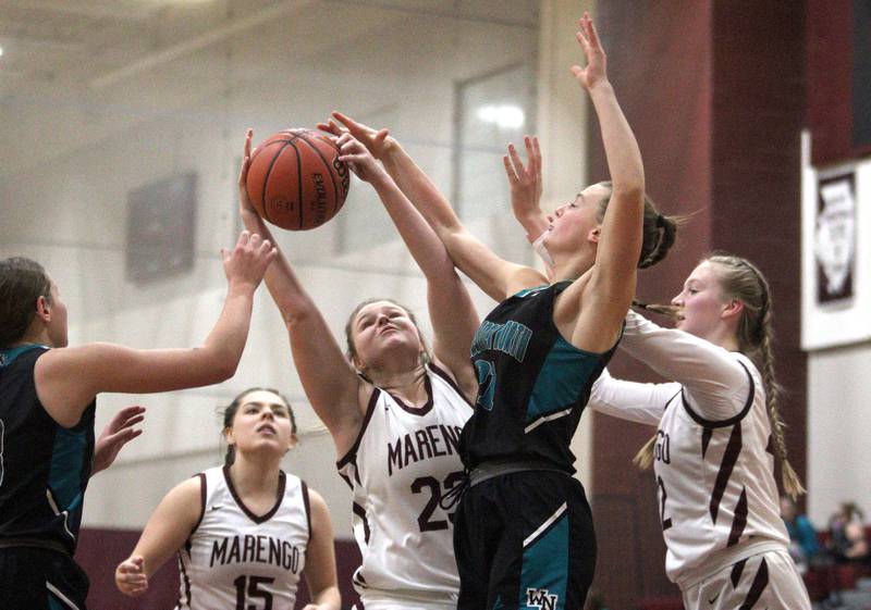 Marengo’s Madison Cannon (23) and Dayna Carr, right, battle Woodstock North’s Isabella Borta for a rebound in varsity girls basketball at Marengo Tuesday evening.