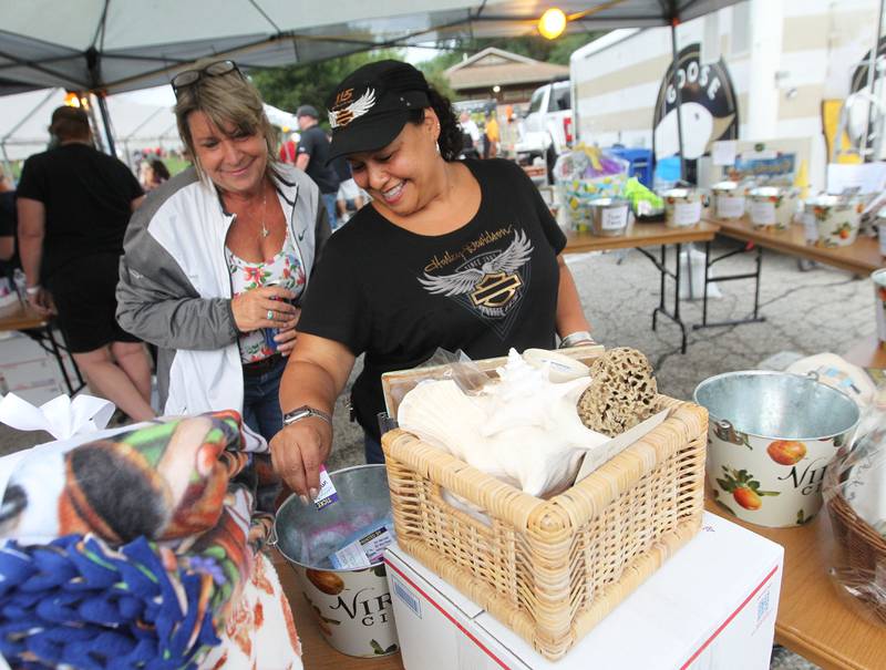 Linda Pacourek, of Lake Villa watches Maeling Botzoc, of Wauconda put raffle tickets into buckets to win a prize during the final concert of the "It’s Thursday” summer concert series on August 10th in Antioch. The event and its proceeds were dedicated to Huntley, a child who was injured during the Taste of Summer in July. 
Photo by Candace H. Johnson for Shaw Local News Network