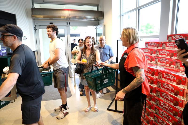 Whole Foods Store Team Leader Kristi Malicoat hands out baskets to customers during the grand opening celebration on Wednesday, June 25, 2025 at the new Whole Foods Market in St. Charles.
