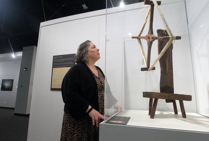 Andi Walker, of Round Lake Beach, visitor services coordinator, looks at a yarn winder used by Maria Ott, of Deerfield, circa 1835 on display Jan. 28 during the opening day of the exhibit "Through Darkness to Light: Photographs Along the Underground Railroad" at the Dunn Museum in Libertyville. The yarn winder was used by Maria and her husband, Lorenz, a tailor by trade, to make a new suit of clothes for Andrew Jackson, a fugitive enslaved man from Mississippi, to continue his journey to Canada on the Underground Railroad.