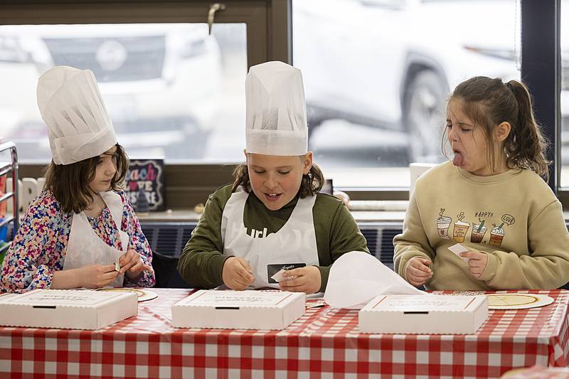 Sterling Washington third grader Maelyn Winge (left) looks on while Jane Miles (right) disagrees with Bentley Rowe’s choice of pizza topping during a math exercise Friday, April 5, 2024.
