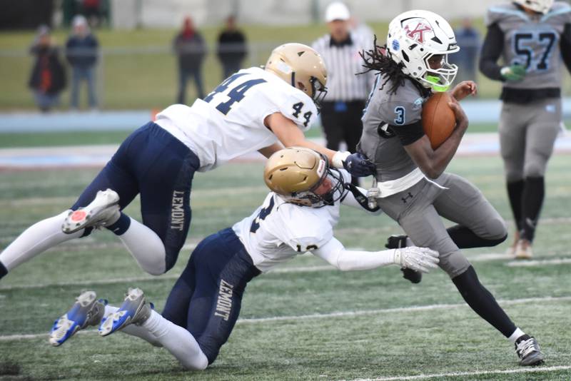 Kankakee's Cedric Terrell III, right, runs past a pair of Lemont defenders during an IHSA Class 5A playoff game at Kankakee Saturday, Nov. 1, 2025.