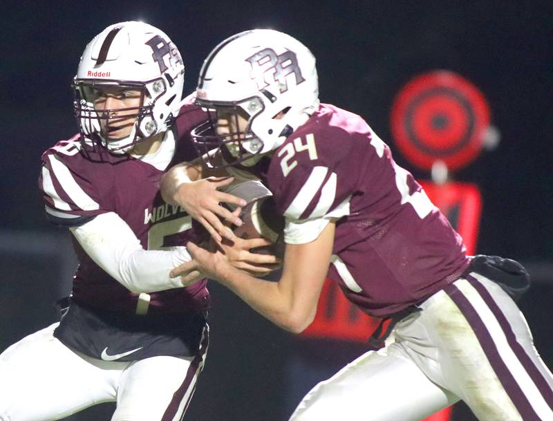 Prairie Ridge’s Luke Vanderwiel, left, hands off to Vincent Byk against Vernon Hills in IHSA football Class 5A first-round playoff action at Prairie Ridge High School in Crystal Lake on Friday, October 31, 2025.