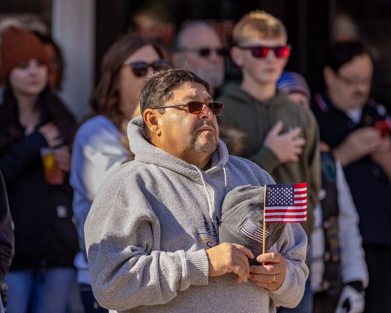 A parade attendee stands at attention as the National Anthem is sung at the beginning of the Utica Veterans Parade and Airshow on November 2, 2025 in Utica.