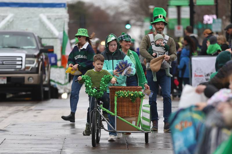 A family travels along the parade route handing out candy at the annual Plainfield Hometown Irish Parade on Sunday, March 15, 2026 in Plainfield.