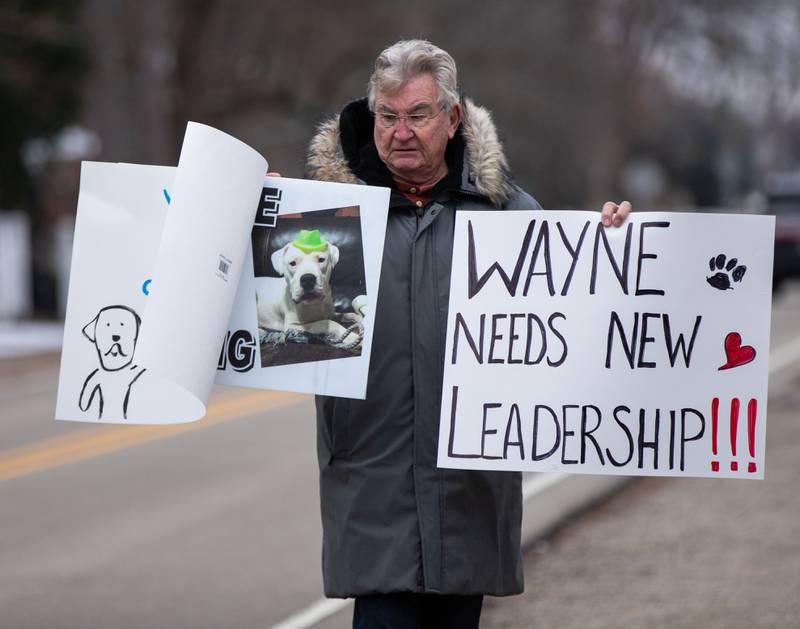 Michael O’Bryan of Campton Hills holds up signs during the Justice for Ludwig protest outside the Little Home Church by the Wayside in Wayne on Saturday, Jan. 7, 2023. Inside the church a town hall meeting took place to discuss an architectural review of the village hall and police department.