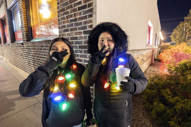 Elizabeth Santiago (left), 12, and Adriana Mata, 12, of Sterling adorn themselves in lights Friday, Dec. 6, 2024, as they tour downtown Sterling for the Sights and Sounds Christmas event.