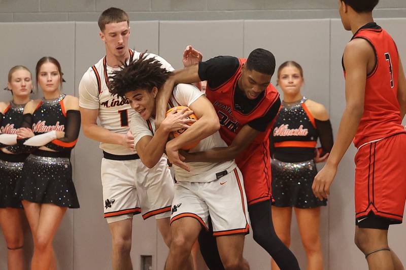 Minooka’s Joe Oyola battles off Bolingbrook’s Jayden Madden for the ball on Tuesday, Dec. 17, 2024 in Minooka.