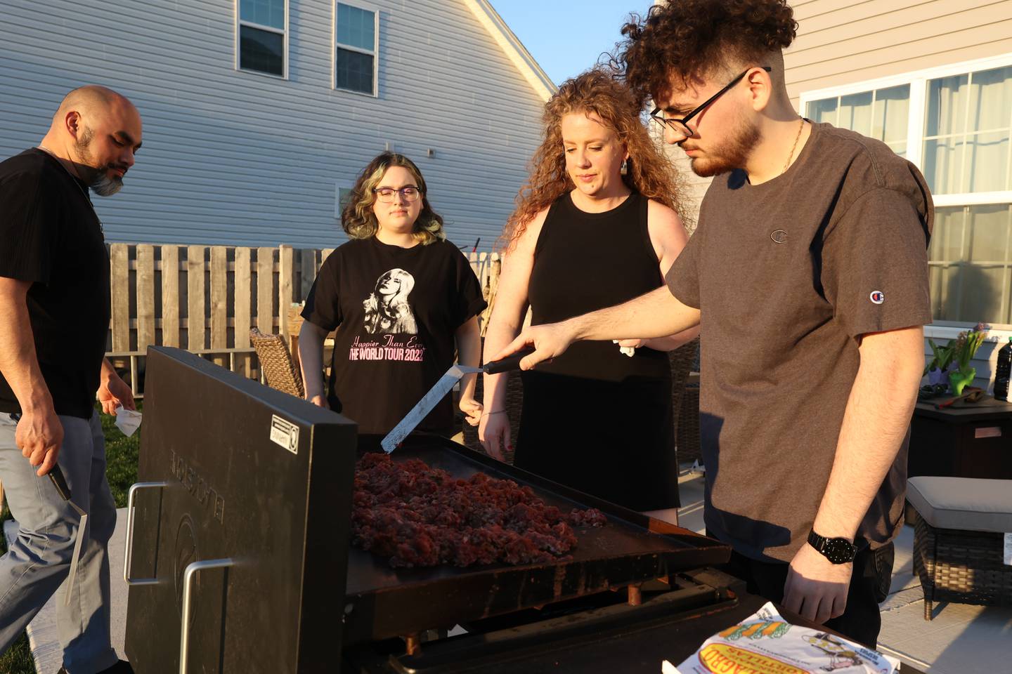 Nicholas Reyes (right) works the grill as the family watches on Wednesday, April 12, 2023 in Joliet.