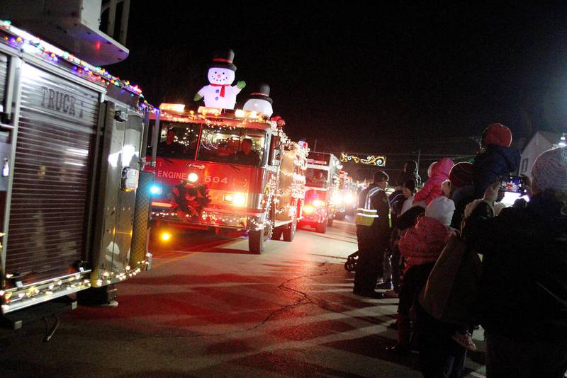 The Oswego Christmas Walk parade, featuring fire trucks from several area fire protection districts, proceeds along Main Street in the village's downtown during last year's annual event.