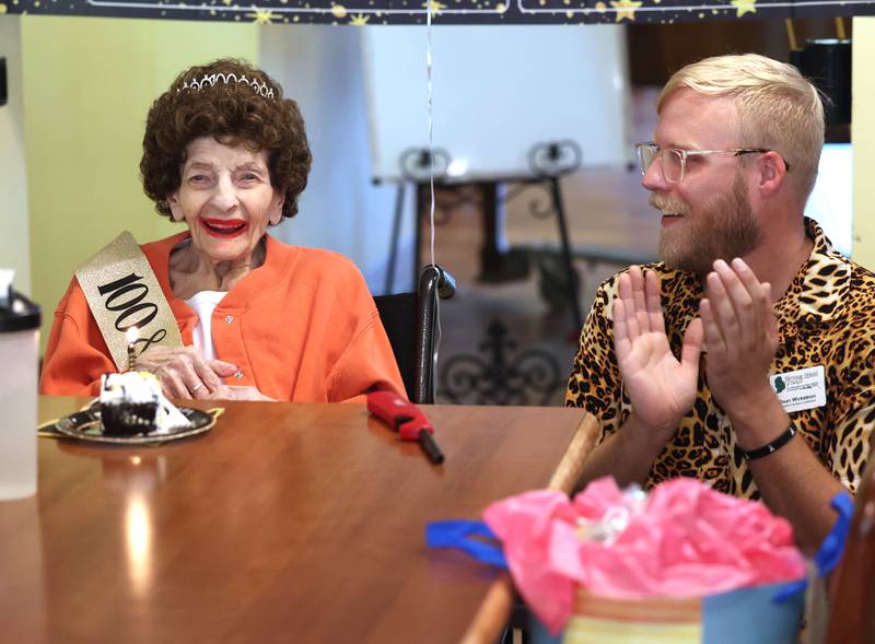 Claire Hubele, a resident at Heritage Woods of DeKalb, smiles as Dean Wickstrom, resident services coordinator at the facility, and other attendees sing “Happy Birthday” to her Wednesday, July 9, 2025, during a party in the cafeteria celebrating her 100th birthday.