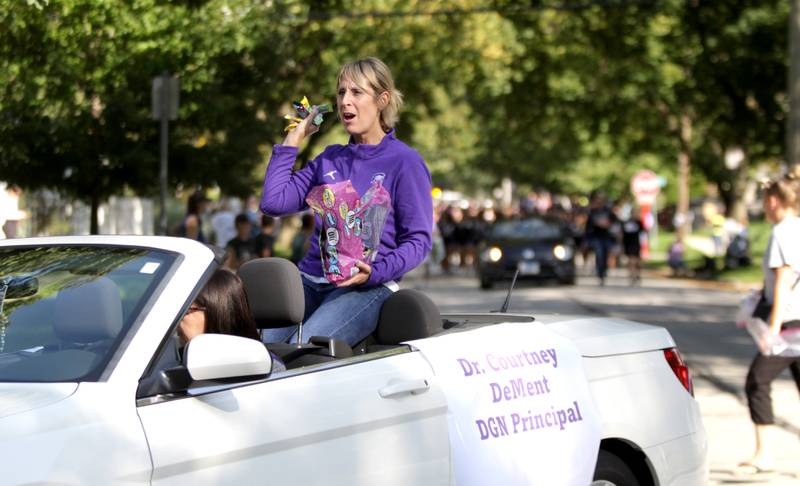 Downers Grove North Principal Courtney DeMent throws candy while riding atop a convertible during the school’s annual homecoming parade on Friday, Sept. 29, 2023.