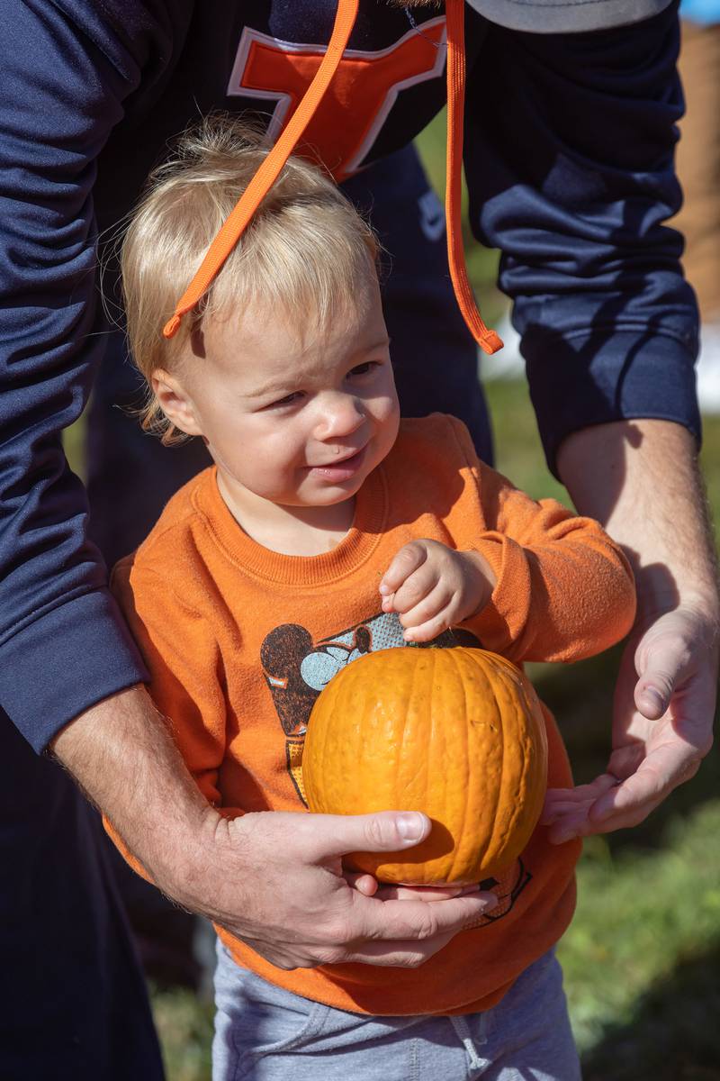 Wyatt Young, 2, of Sterling gets some help from his dad while holding his prized pumpkin