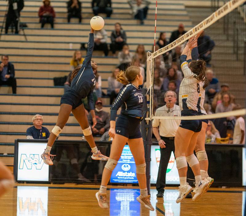 Oswego East's Cailyn Smiley (14) goes up for a kill against Neuqua Valley during the Neuqua Valley 4A regional final volleyball match at Neuqua Valley High School in Naperville on Thursday, Oct 27, 2022.