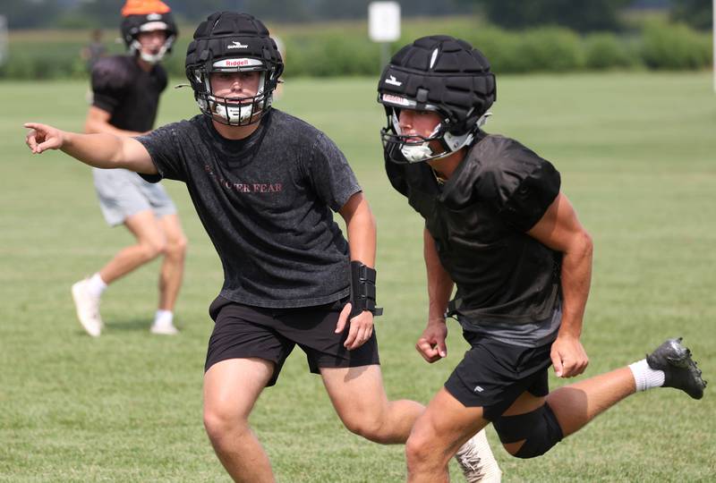 Kaneland’s Jackson Little (left) picks up a receiver during a play Monday, Aug. 18, 2025, during practice at the school in Maple Park.