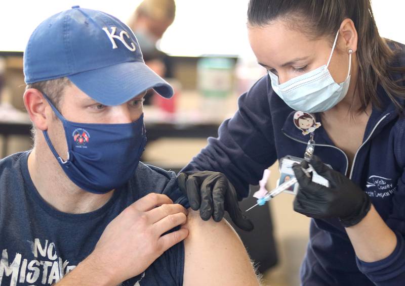 Travis Karr, a City of DeKalb firefighter/paramedic, receives an injection of the Moderna COVID-19 vaccine from DeKalb County Health Department public health nurse Alex Diehl Thursday in DeKalb.