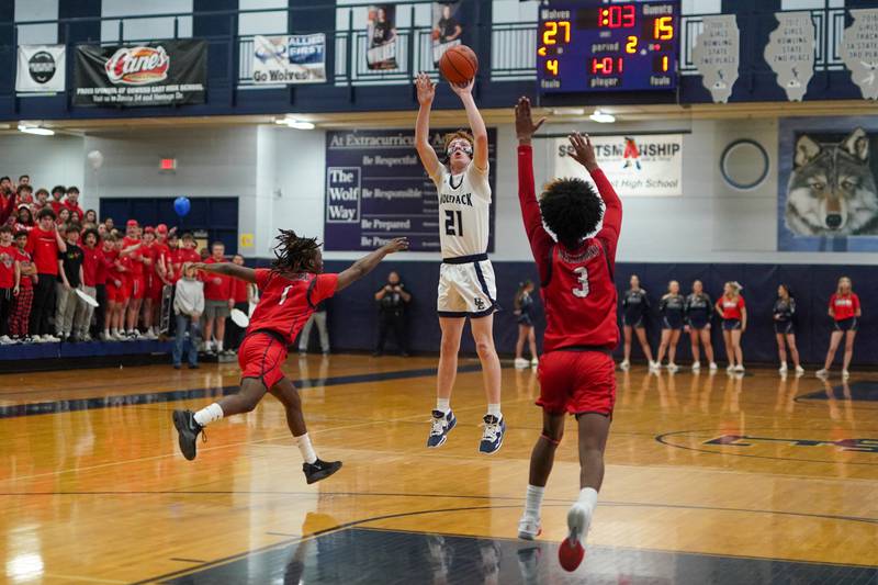 Oswego East's Andrew Pohlman (21) shoots a three pointer against West Aurora's Donta’e Woods (1) and Jayvyn Marion (3) during a basketball game at Oswego High School on Friday, Feb 2, 2024.