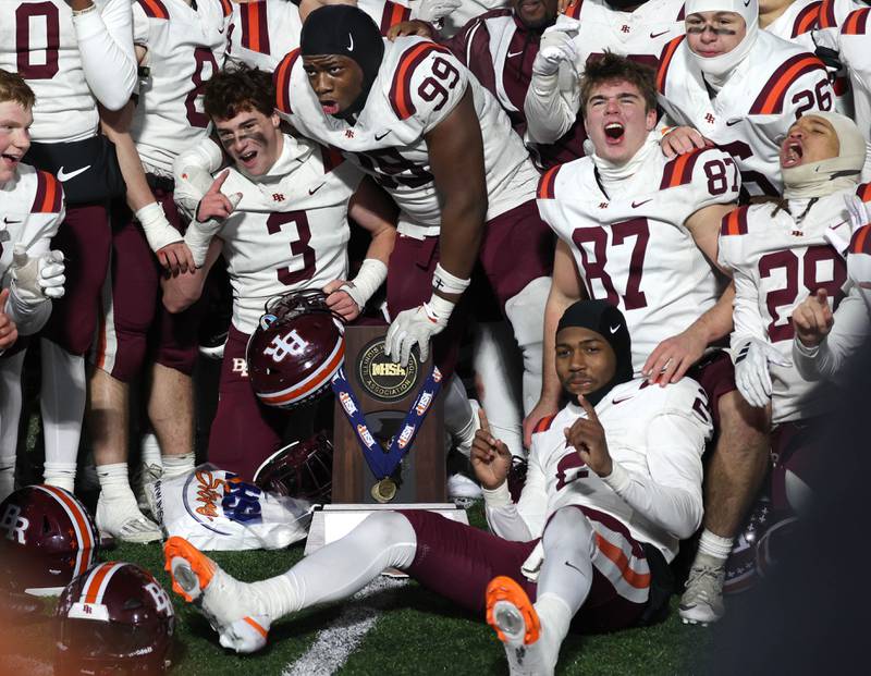 Brother Rice players celebrate sith the trophy Wednesday, Dec. 3, 2025, after their IHSA Class 7A state chamionship win over St. Rita in Huskie Stadium at Northern Illinois University in DeKalb.