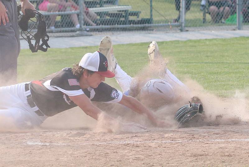 Spring Valley's Jack Jablonski misses a tag on Michigan's Austin O'Dell at the plate on a pass ball during the Central Region Baseball Tournament on Monday, July 24, 2023 at Washington Park in Peru.