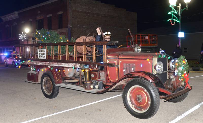 Mt. Morris Fire Chief Rob Hough IV waves to the crowd as he drives the fire department's 1930 antique truck in the lighted parade during Mt. Morris' Christmas in the Village on Saturday, Dec. 7, 2024.