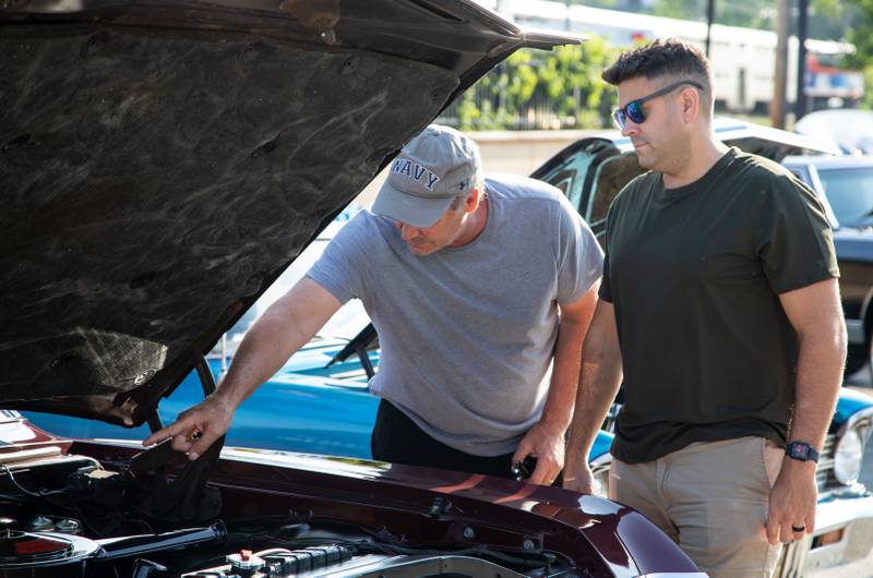 David Dellipaoli, right, and a person who declined to be named look in the engine of a car during the Moose Cruise Night at the Moose Lodge in Downers Grove on Friday, June 3, 2023.