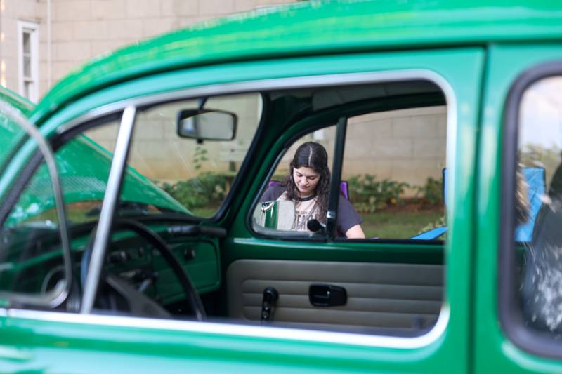 Eve Boeckmann sits with the 1972 Volkswagen Beetle owned by her father, Steve Boeckmann, both of Bourbonnais, during the Cruise-In Night at the Museum on Thursday, Aug. 14, 2025.