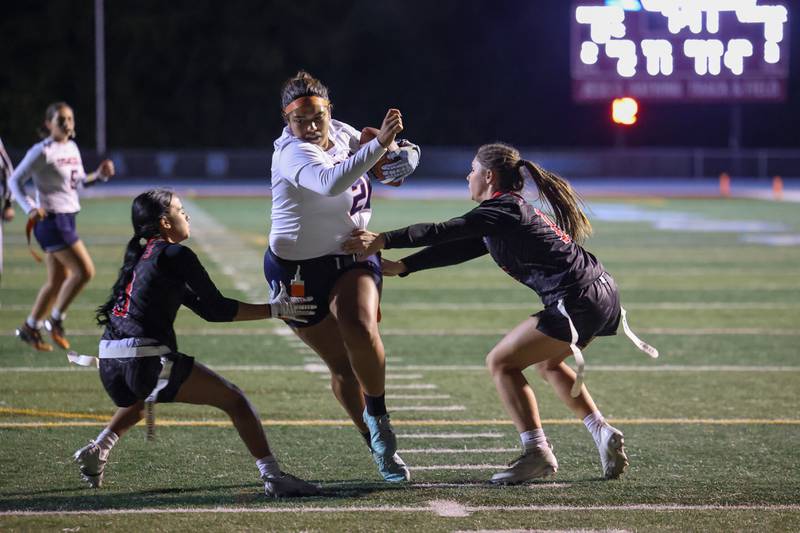 Oswego's Nathalia Wheeler runs the ball as Yorkville's Allena Triner, left, and Hayden Hodges grab for flags during the Foxes' 2-1 overtime victory over Oswego in the IHSA Kankakee Regional championship game on Thursday, Oct. 9, 2025.